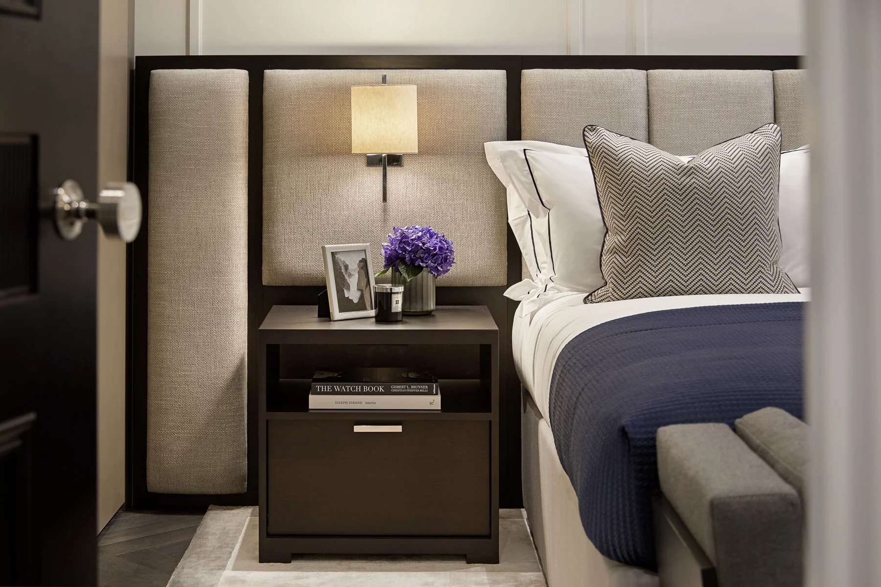 Detail photograph of a bed and side table with plant and picture frame.