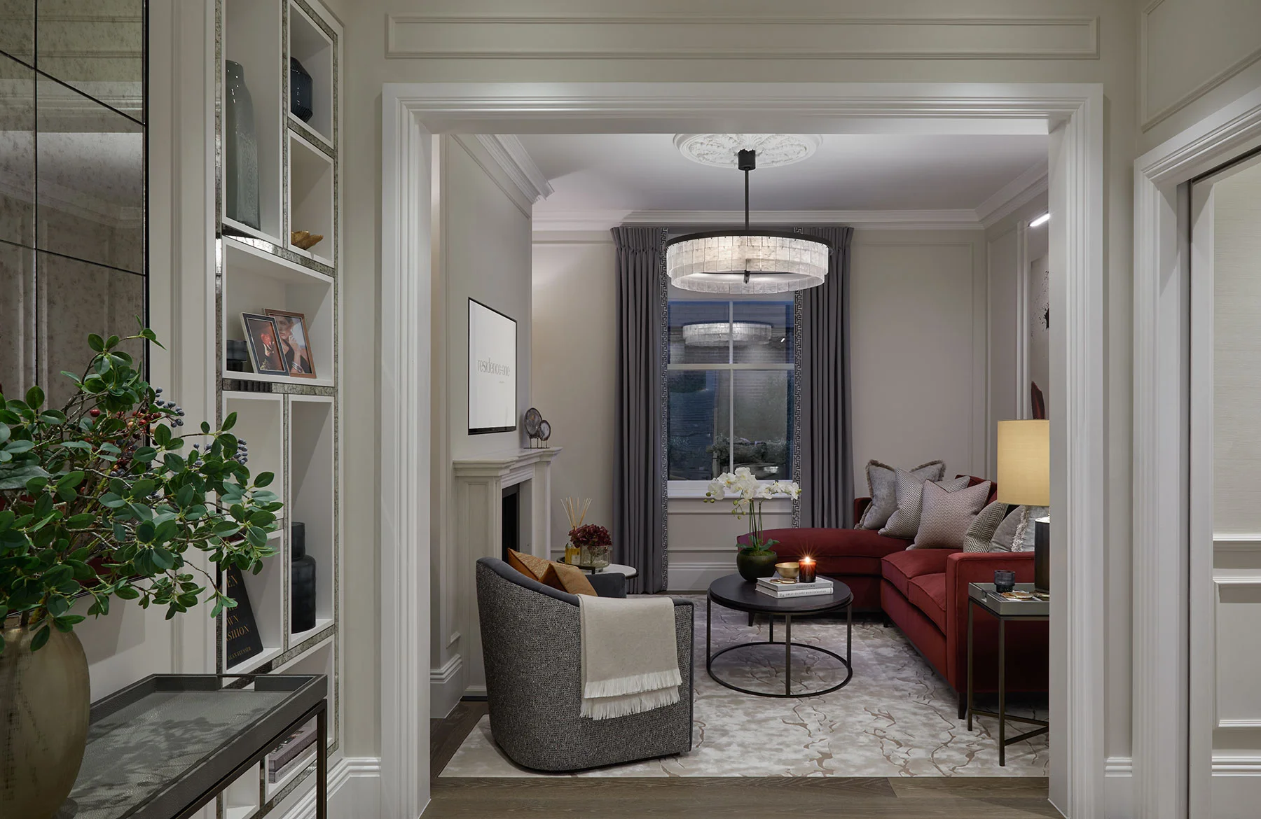 Elegant living room with a red sofa, round coffee table, and a calming view through a large window. Decorated with plants.