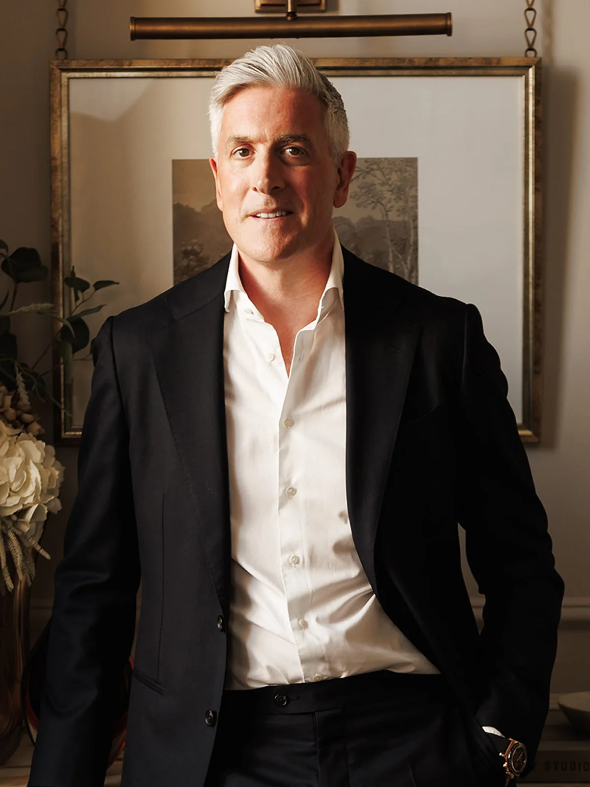 Portrait of a male interior design founder wearing a dark suit in a refined residential interior.