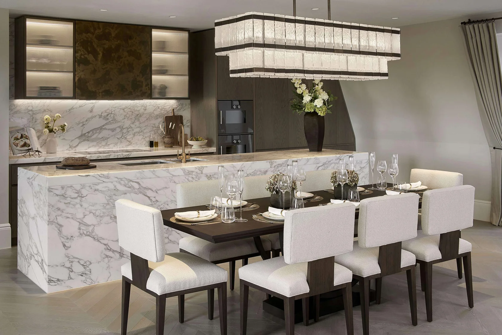 Luxury kitchen and dining area with marble island, bespoke cabinetry, and statement pendant lighting.