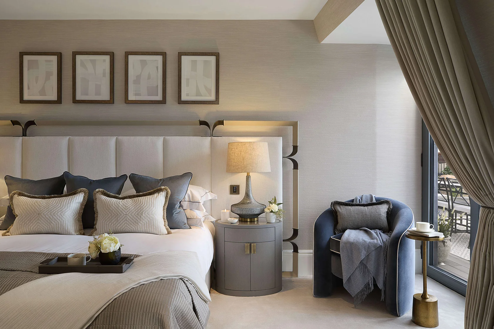 Bedroom styling detail featuring textured cushions, bedside table, and sculptural lamp.