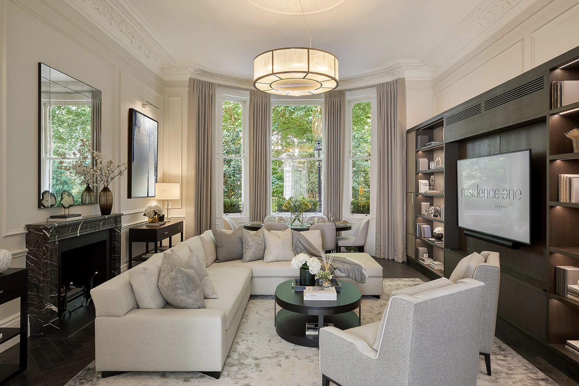 Elegant formal living room with bespoke shelving, curved seating, and statement ceiling light.