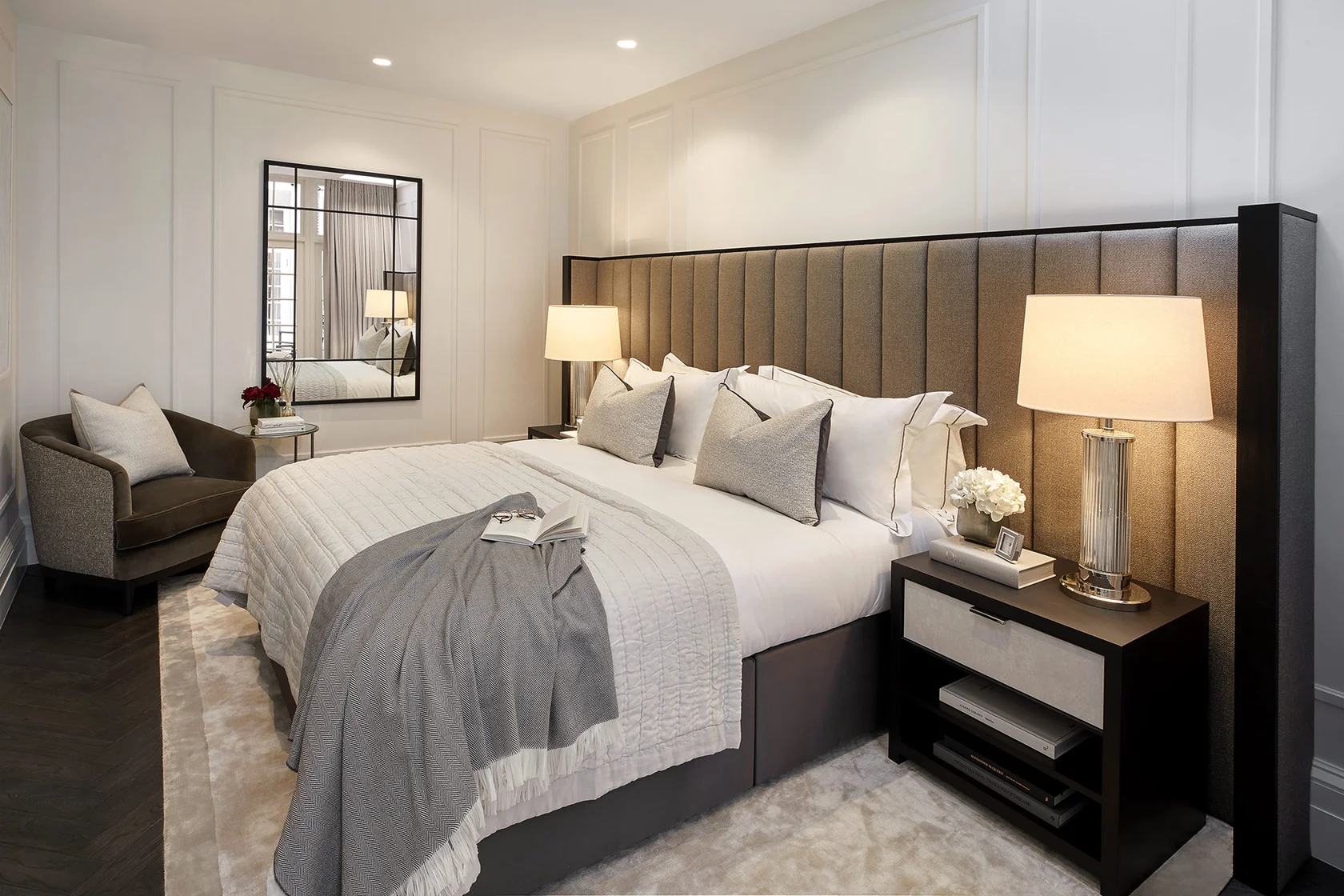 Primary bedroom with upholstered headboard, tailored bedding, and soft ambient lighting.