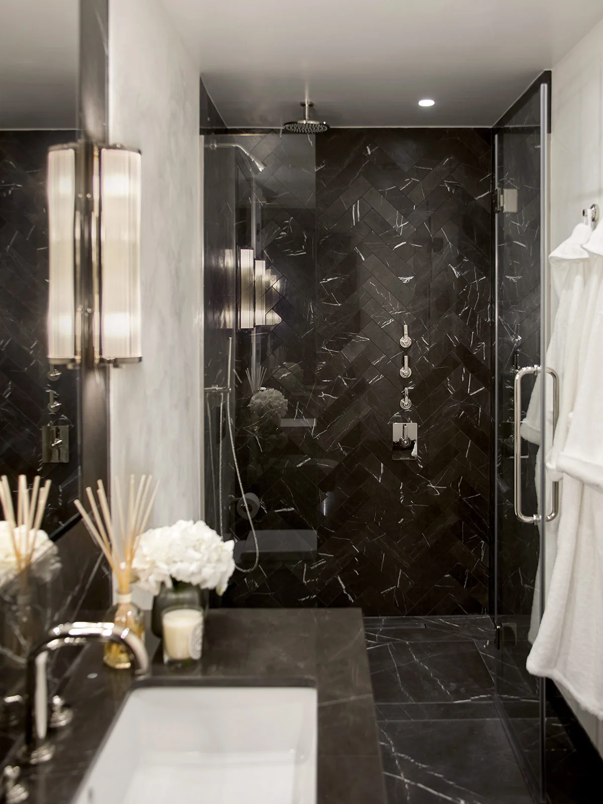 Luxury shower room with dark stone tiles, glass enclosure, and contemporary fittings.