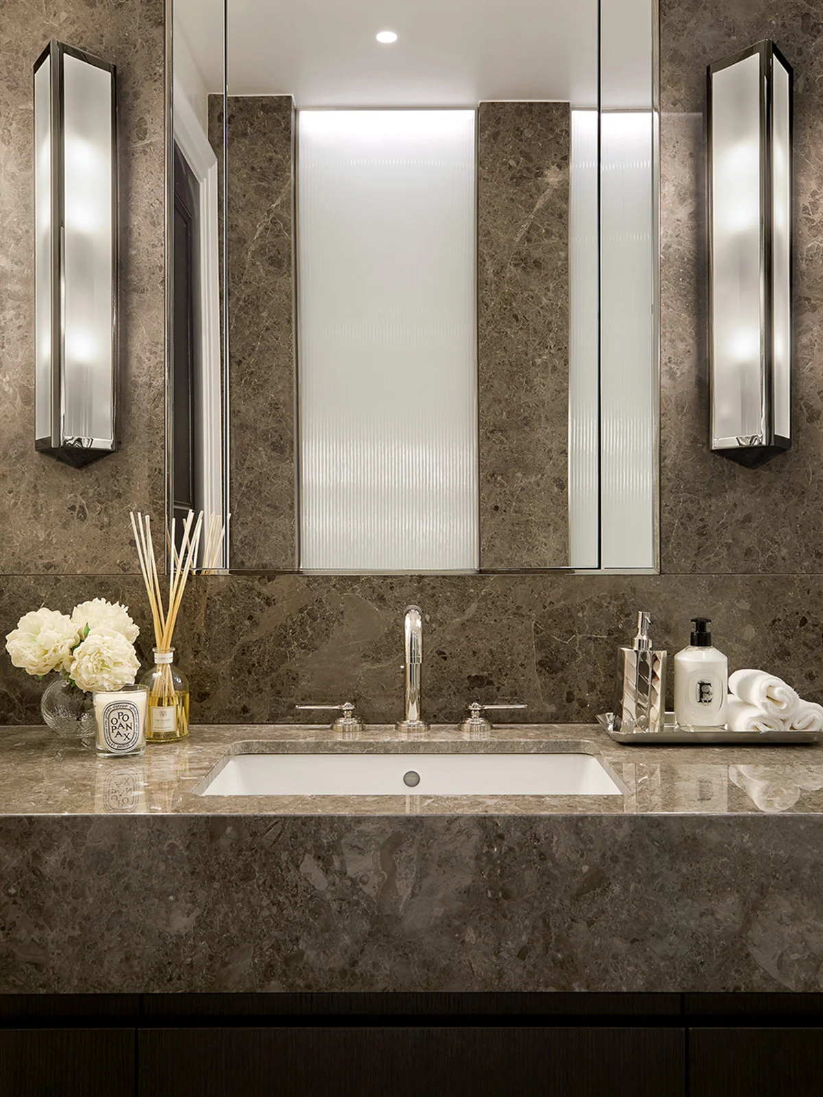Luxury bathroom vanity with marble countertop, integrated basin, mirrored cabinets, and polished chrome fittings.