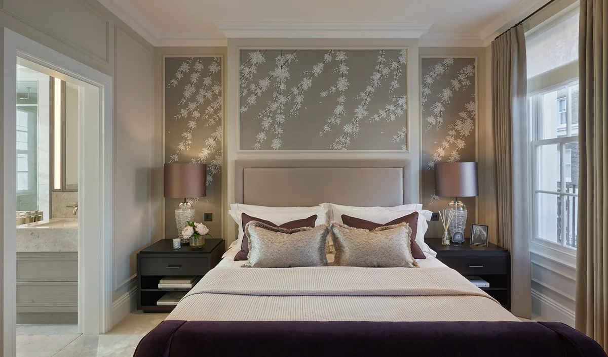 Elegant primary bedroom with symmetrical bedside tables, layered textiles, and soft lighting.