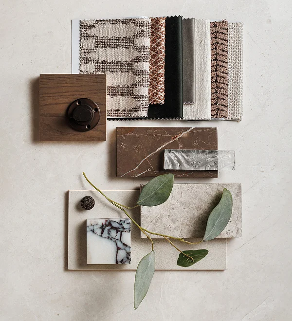 Flat lay of interior design materials including fabric samples, stone finishes, and wood textures.