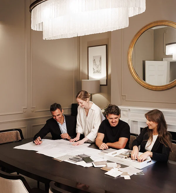 Interior design and development team reviewing plans and material samples around a conference table.