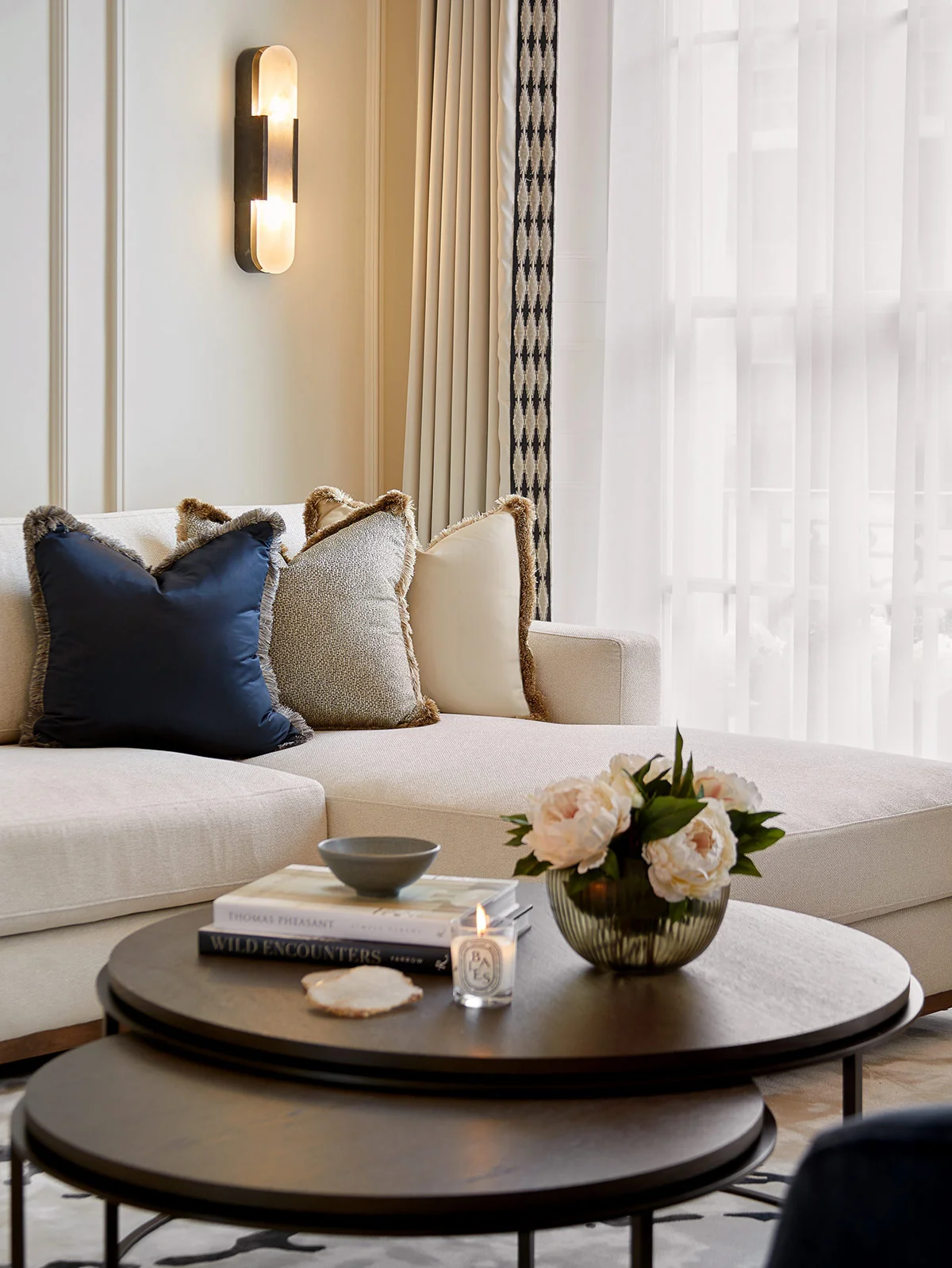 Cozy living room interior featuring a light sofa with decorative pillows and a coffee table adorned with flowers.