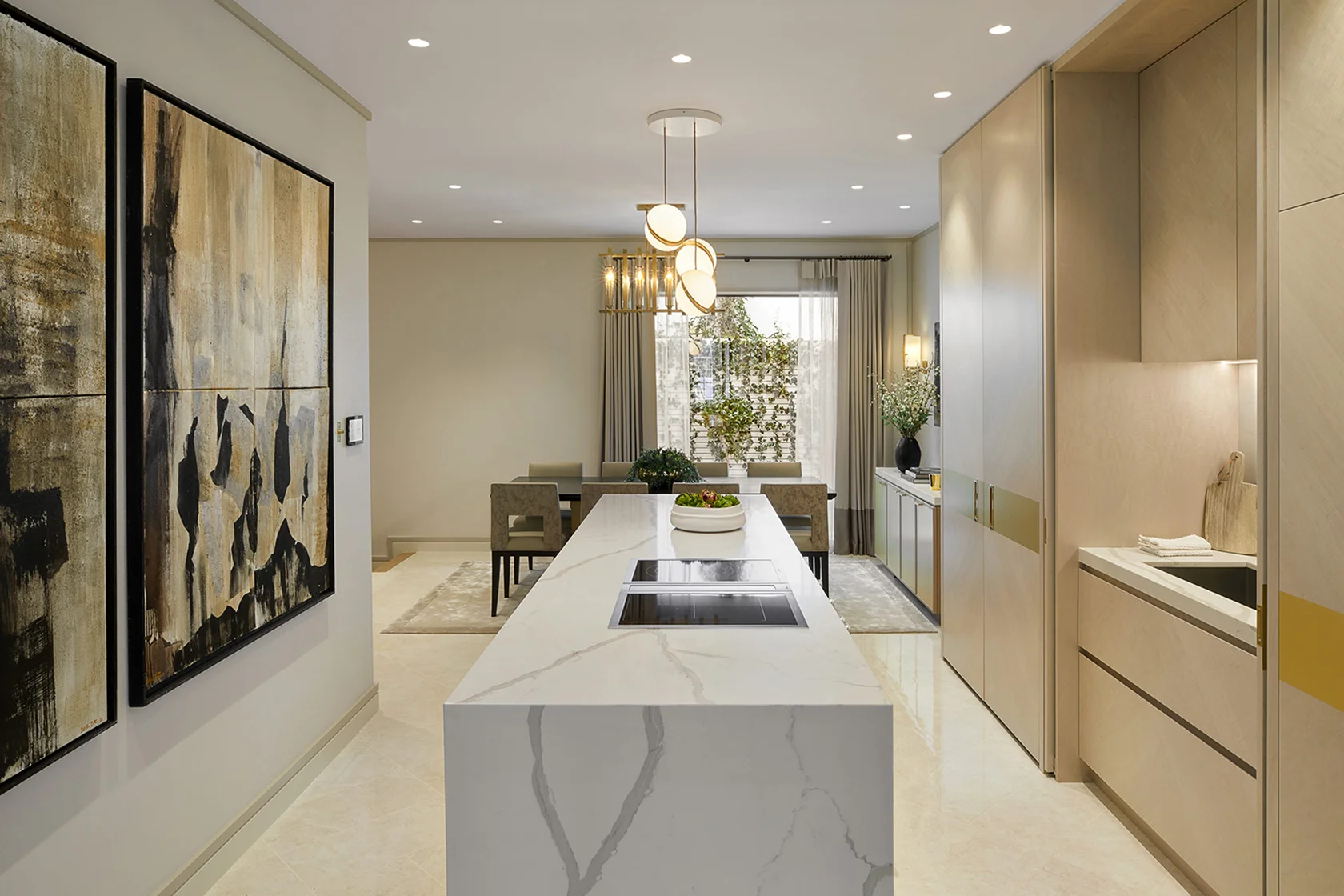 Modern kitchen with marble island, stylish cabinetry, and abstract art on the walls, creating a bright and elegant space.