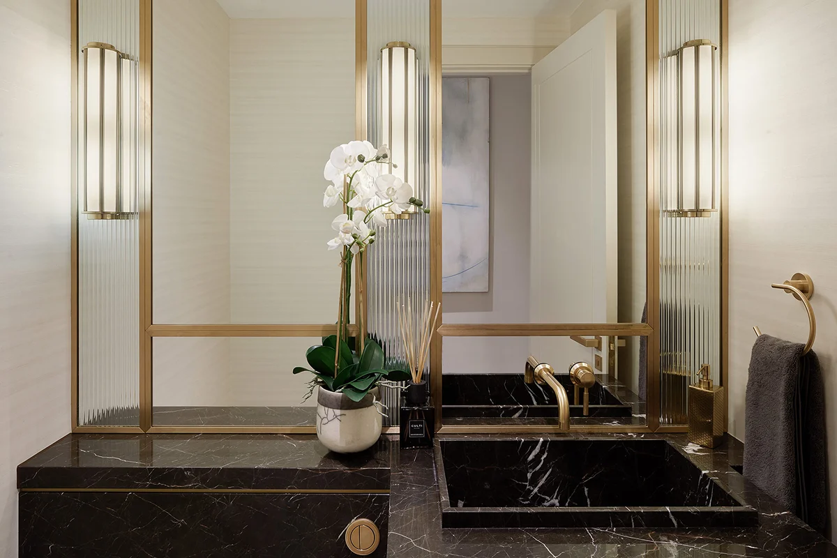 Modern bathroom featuring a dark marble countertop, elegant fixtures, and a potted orchid in a decorative planter.