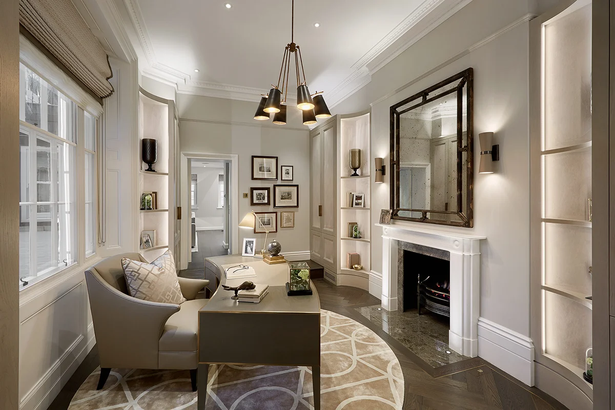 Modern office space with a round rug, seating area, and stylish decor, featuring a fireplace and framed artwork on the walls.