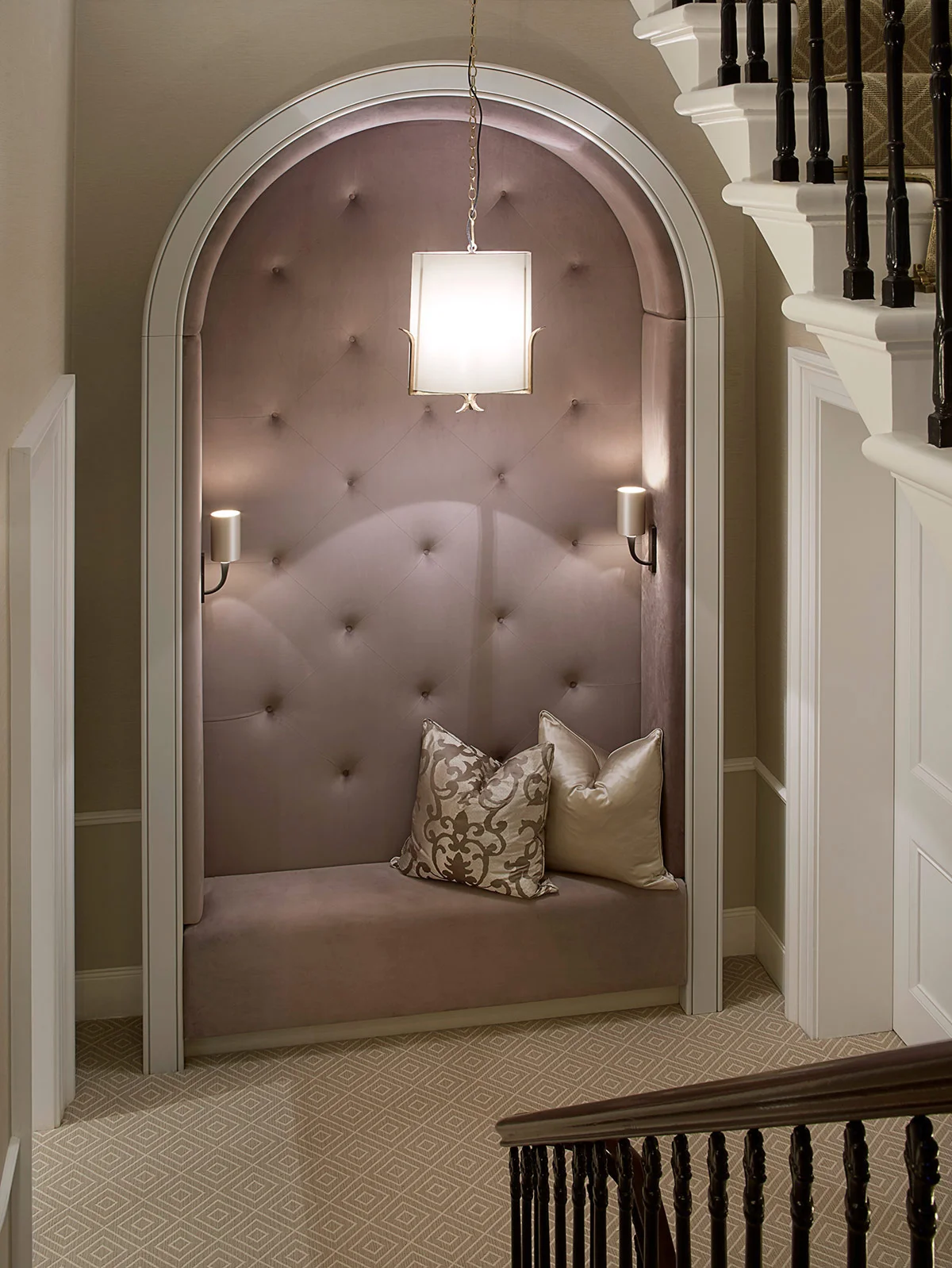 Cozy upholstered nook with decorative pillows and soft lighting, adjacent to a staircase.