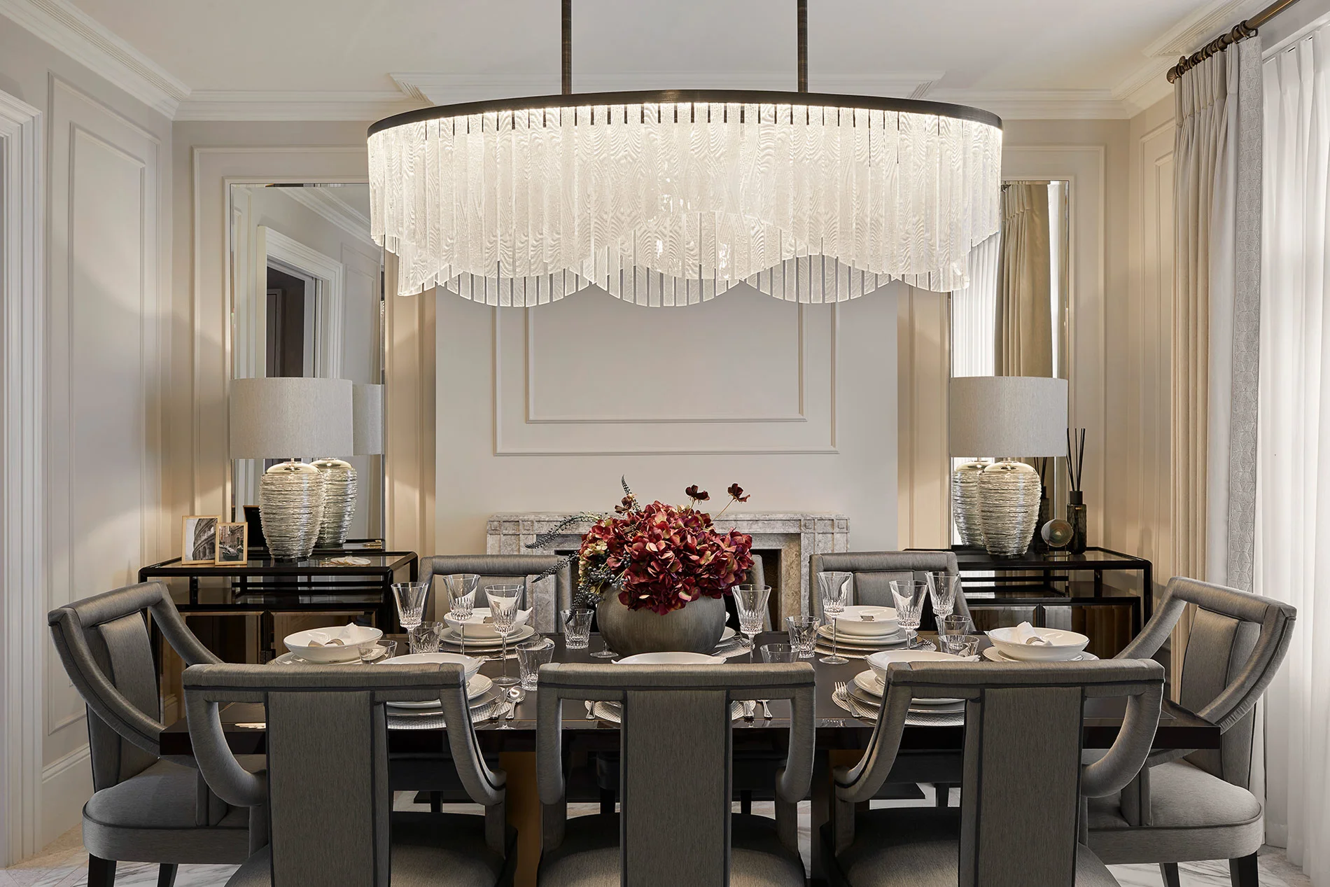 Elegant dining room with a large chandelier, a floral centerpiece, and stylish table settings.