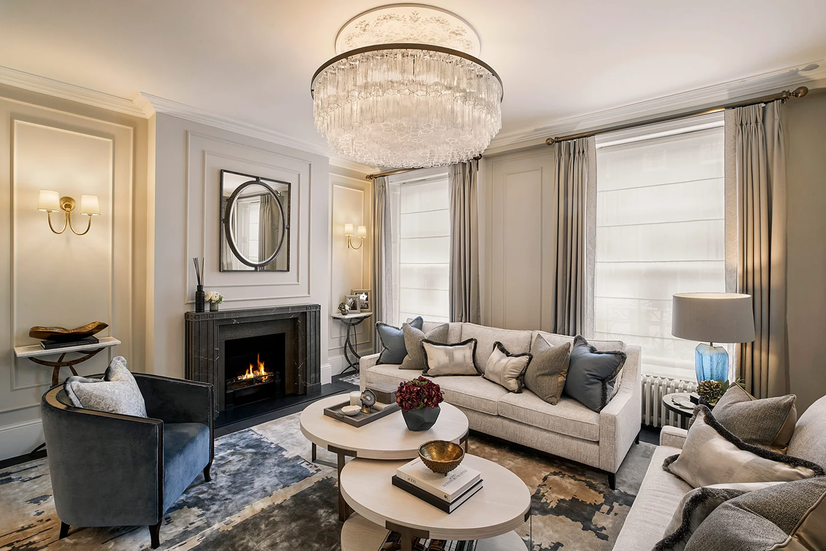 Luxurious living room with a chandelier, a white sofa, armchair, and cozy fireplace, accented by elegant decor.