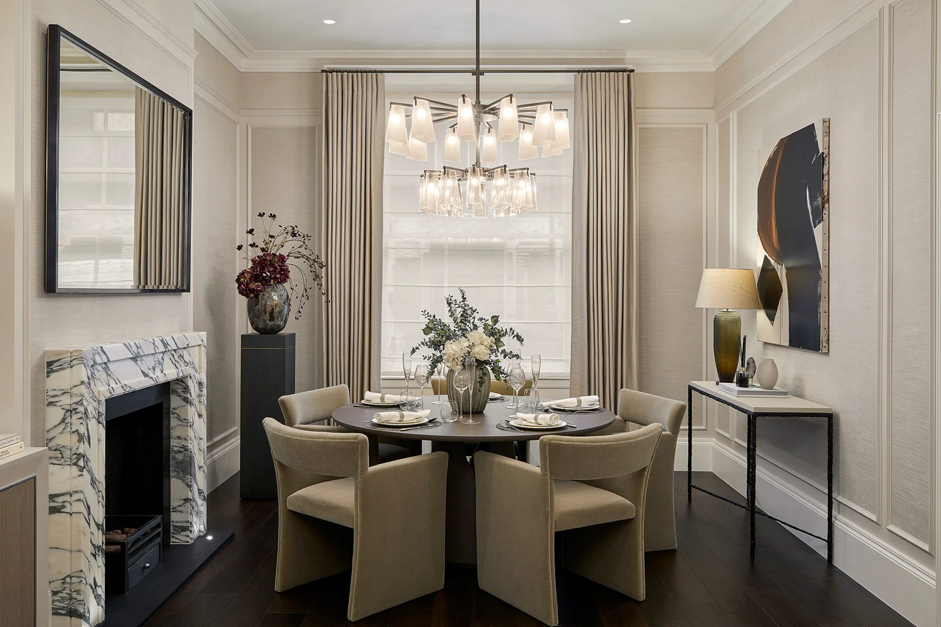 Elegant dining room featuring a round table with chairs, chandelier, and decorative elements in a bright, stylish setting.