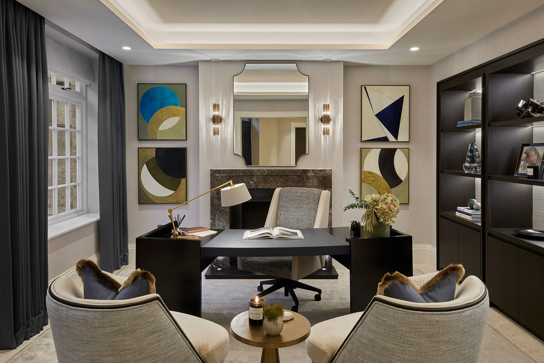 Modern workspace featuring a black desk, two chairs, wall art, a mirror, and a bookshelf with stylish decor.