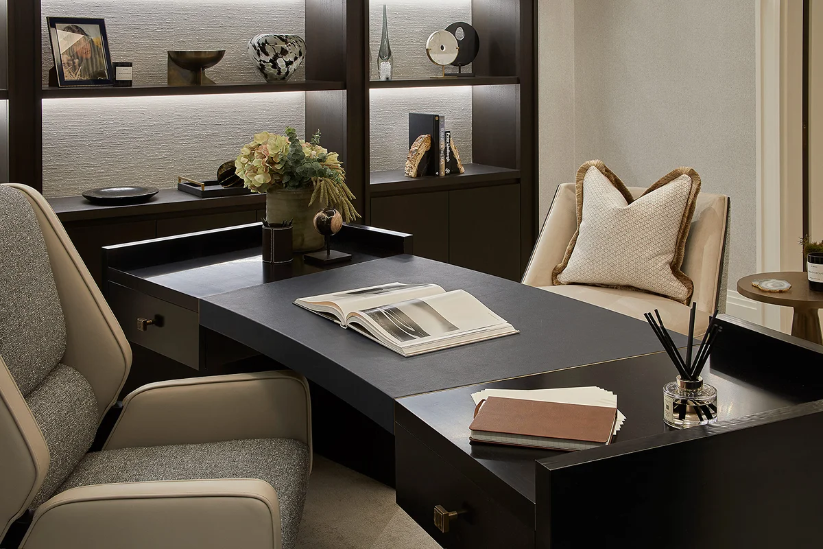 Modern office space featuring a sleek black desk, comfortable chairs, and decorative shelves with objects and plants.