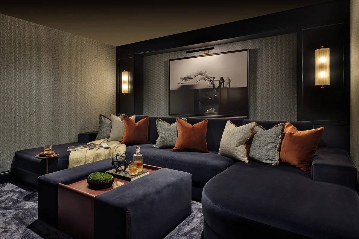 Cozy lounge with dark blue seating, decorative cushions, a coffee table, and atmospheric wall lighting.