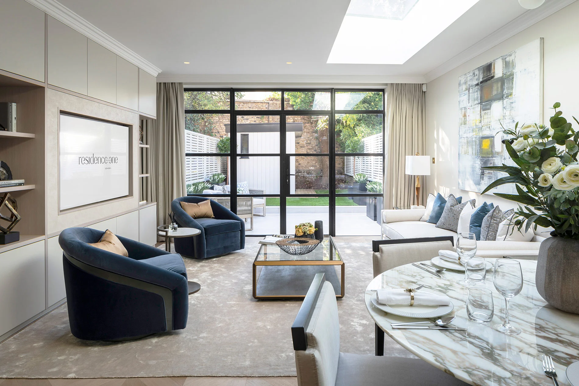 Modern living room with glass doors, stylish furniture, and greenery visible outside. Elegant decor with a dining area.