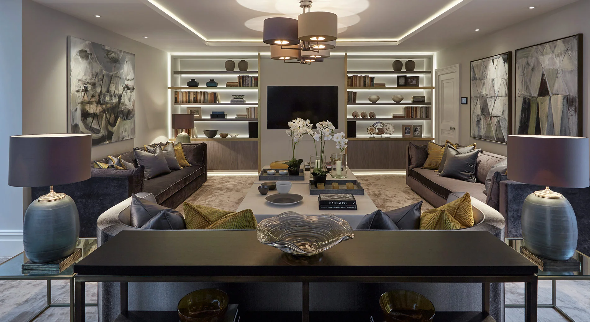 Modern living room with elegant furniture, decorative vases, and shelves featuring art and books, illuminated by soft